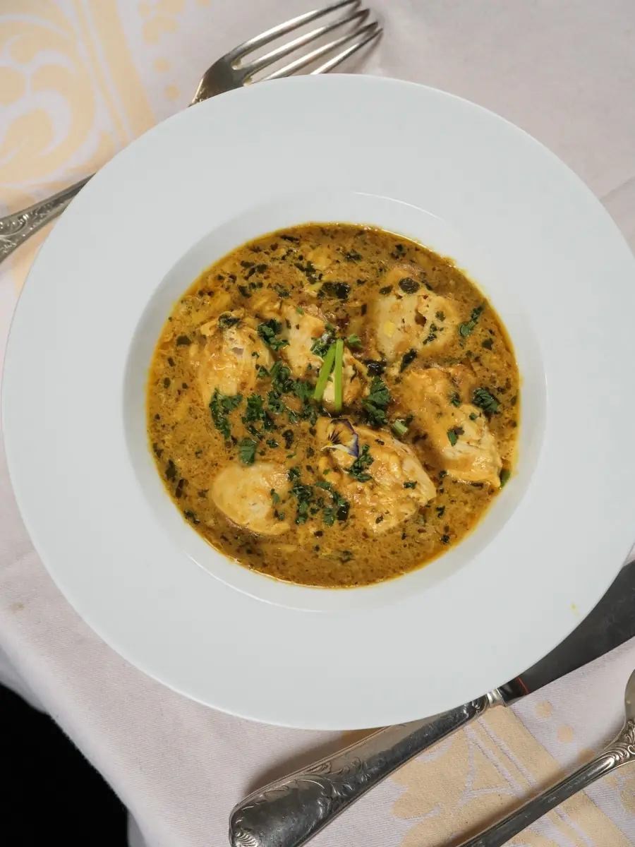 Golden curry with fresh herbs in a deep plate
